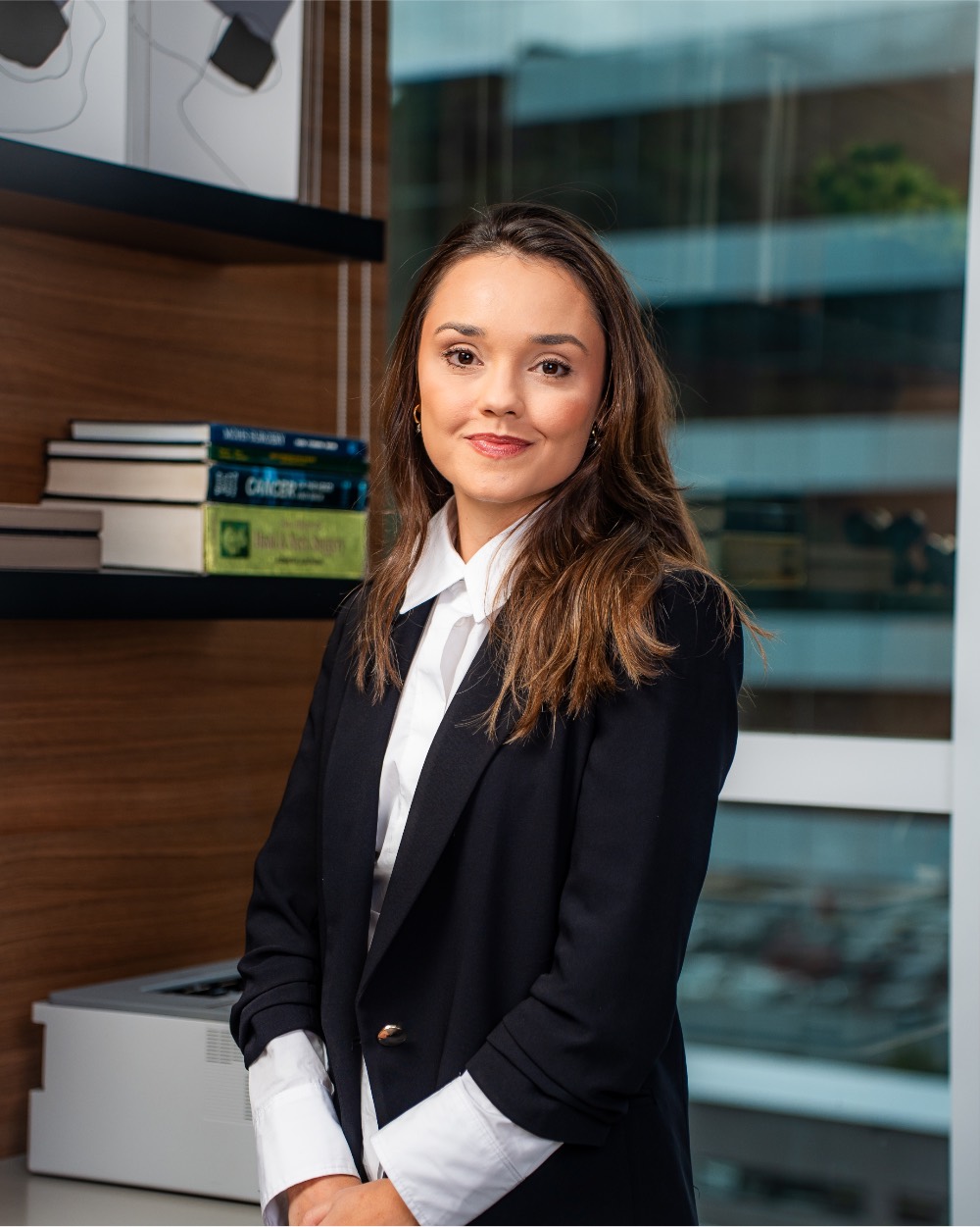 Retrato corporativo de profissional em escritório, com fachada de vidro ao fundo