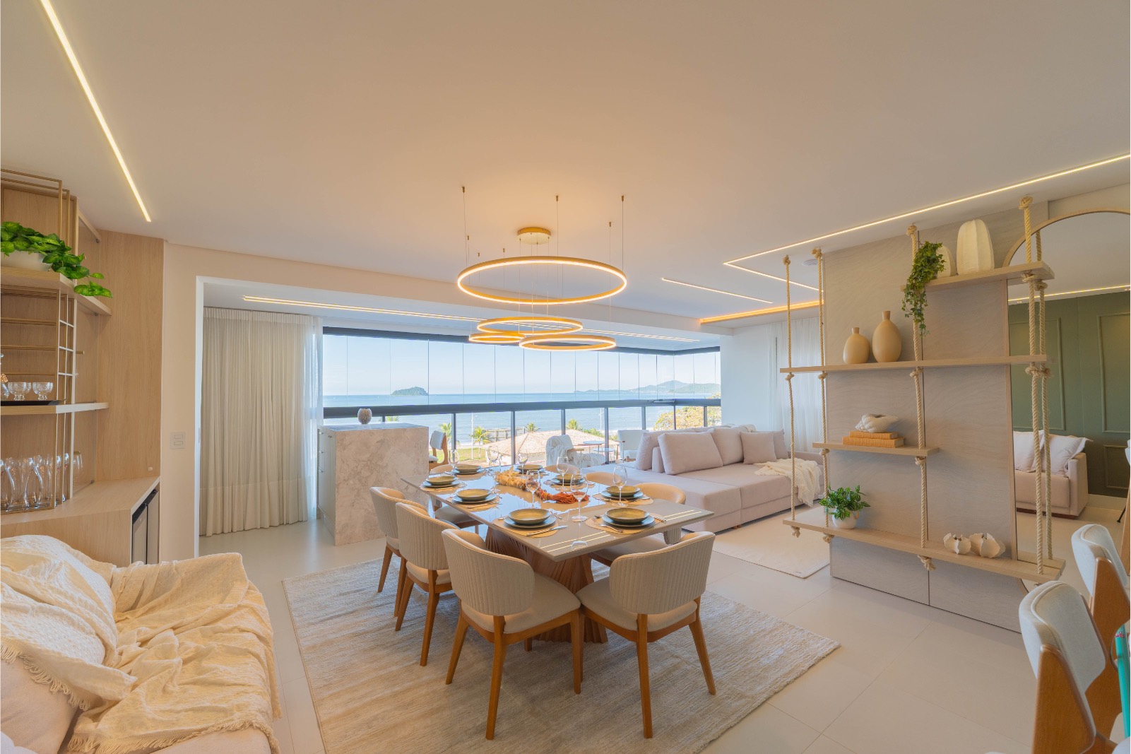Sala de estar e jantar integradas, com mesa posta e vista para o mar